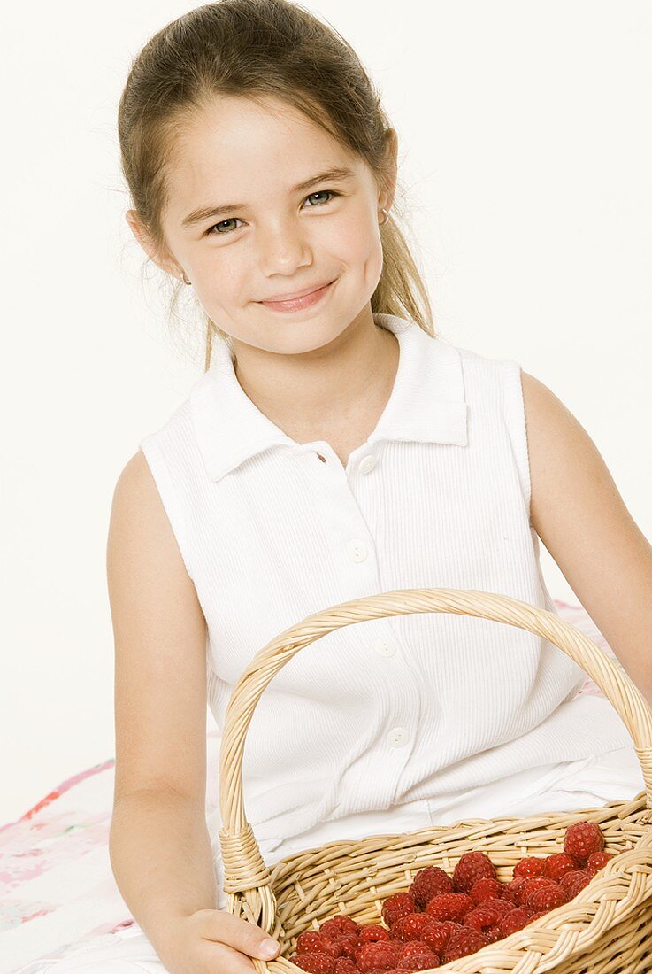 Girl holding basket of fresh raspberries