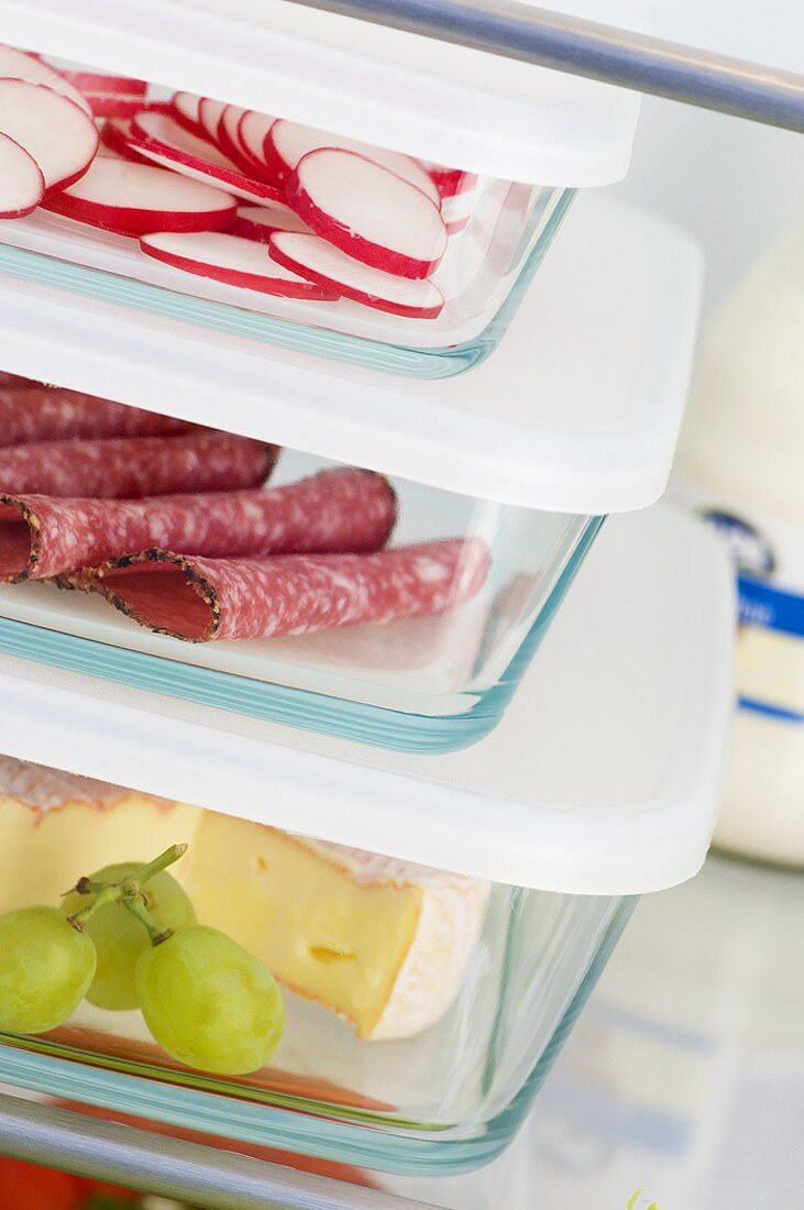 Cheese, salami & radishes in food storage boxes in fridge