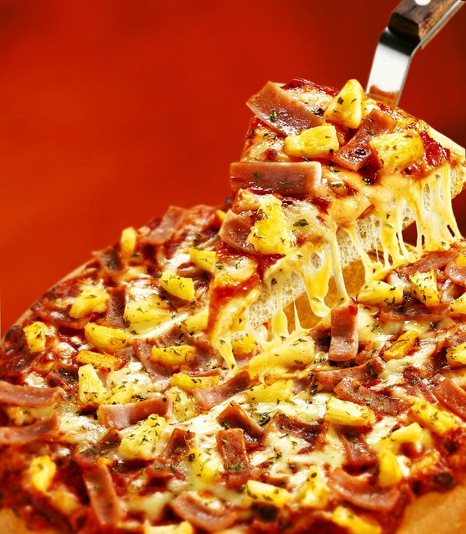 Pizza mit Schinken und Ananas, ein Stück auf Pizzaheber