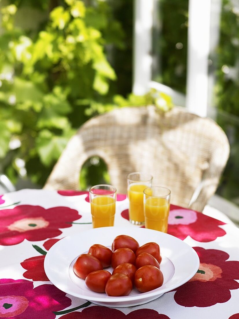 Tomatoes and orange juice on a table out of doors