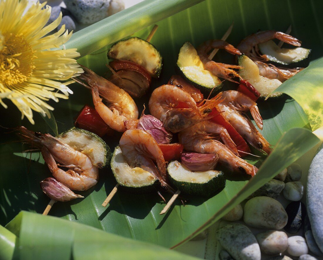 Skewered prawns, courgettes and garlic on banana leaf