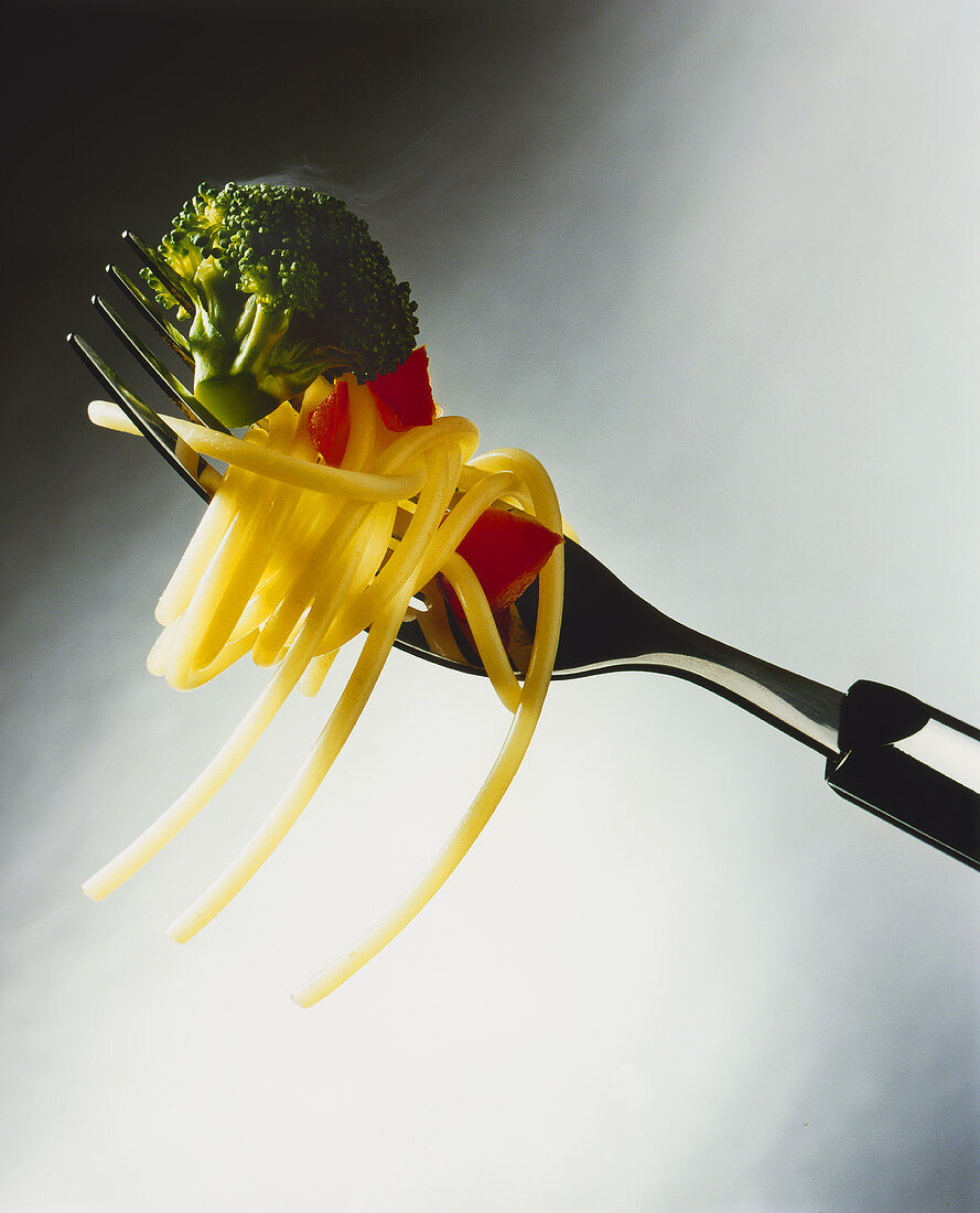 Spaghetti and vegetables on fork