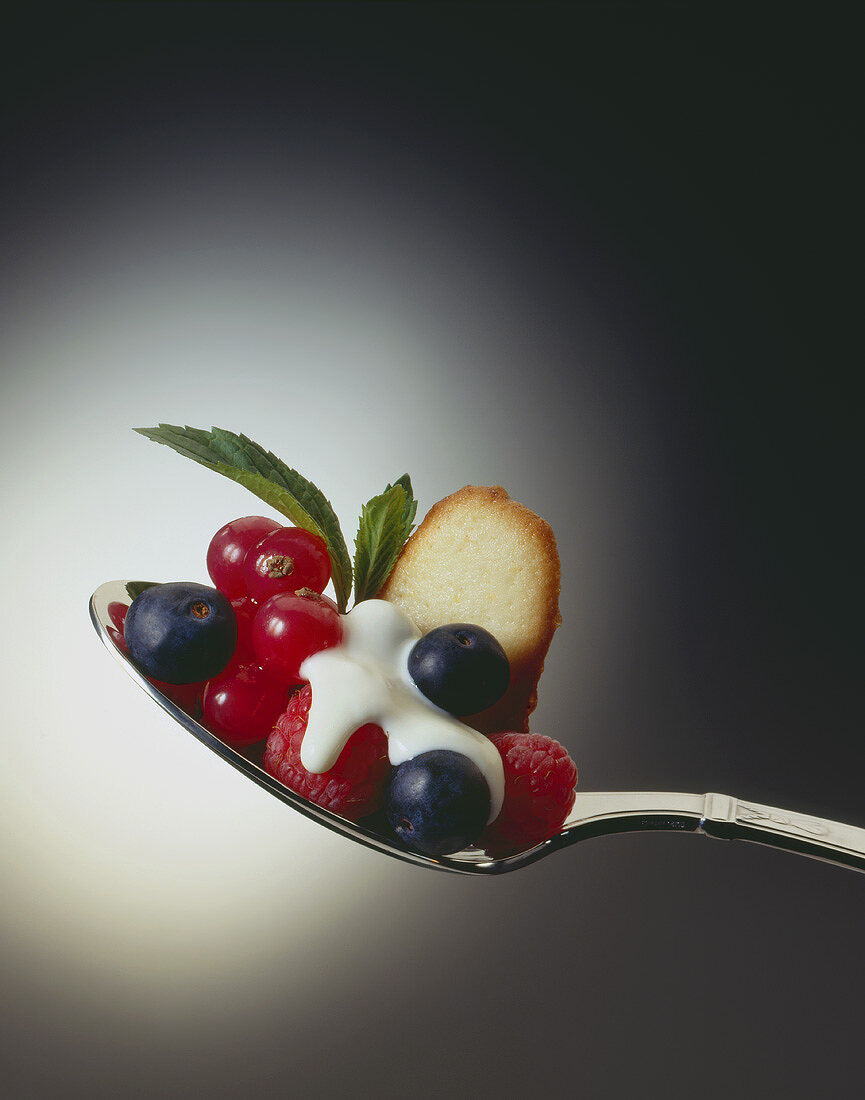 Frische Beeren mit Sahne und Gebäck auf Löffel