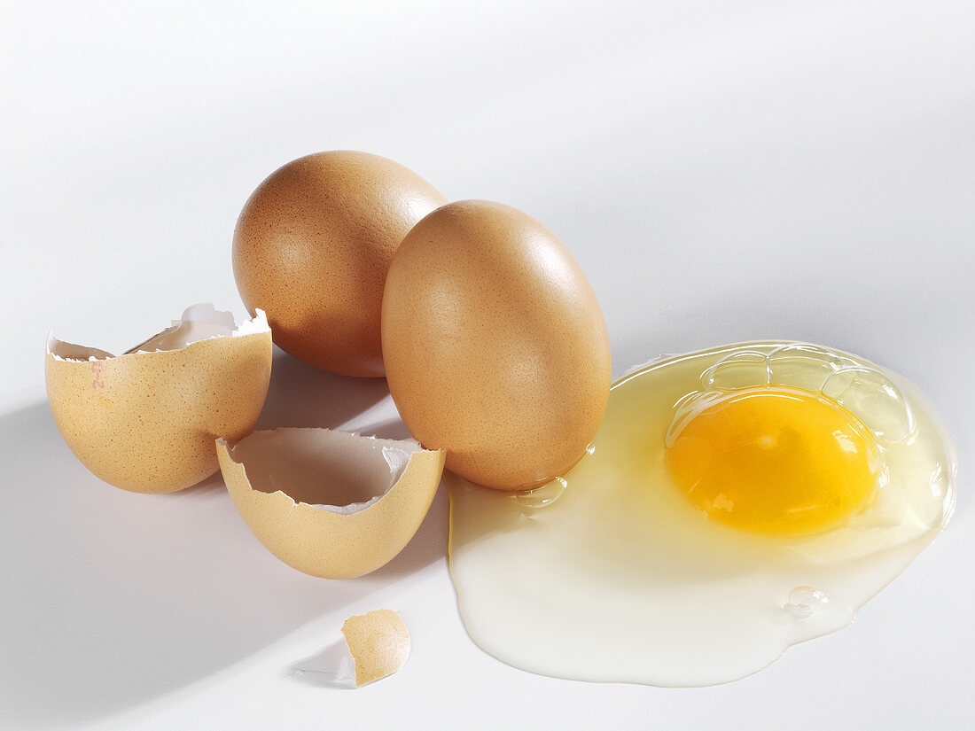 Aufgeschlagenes Ei mit Schale und ganze Eier