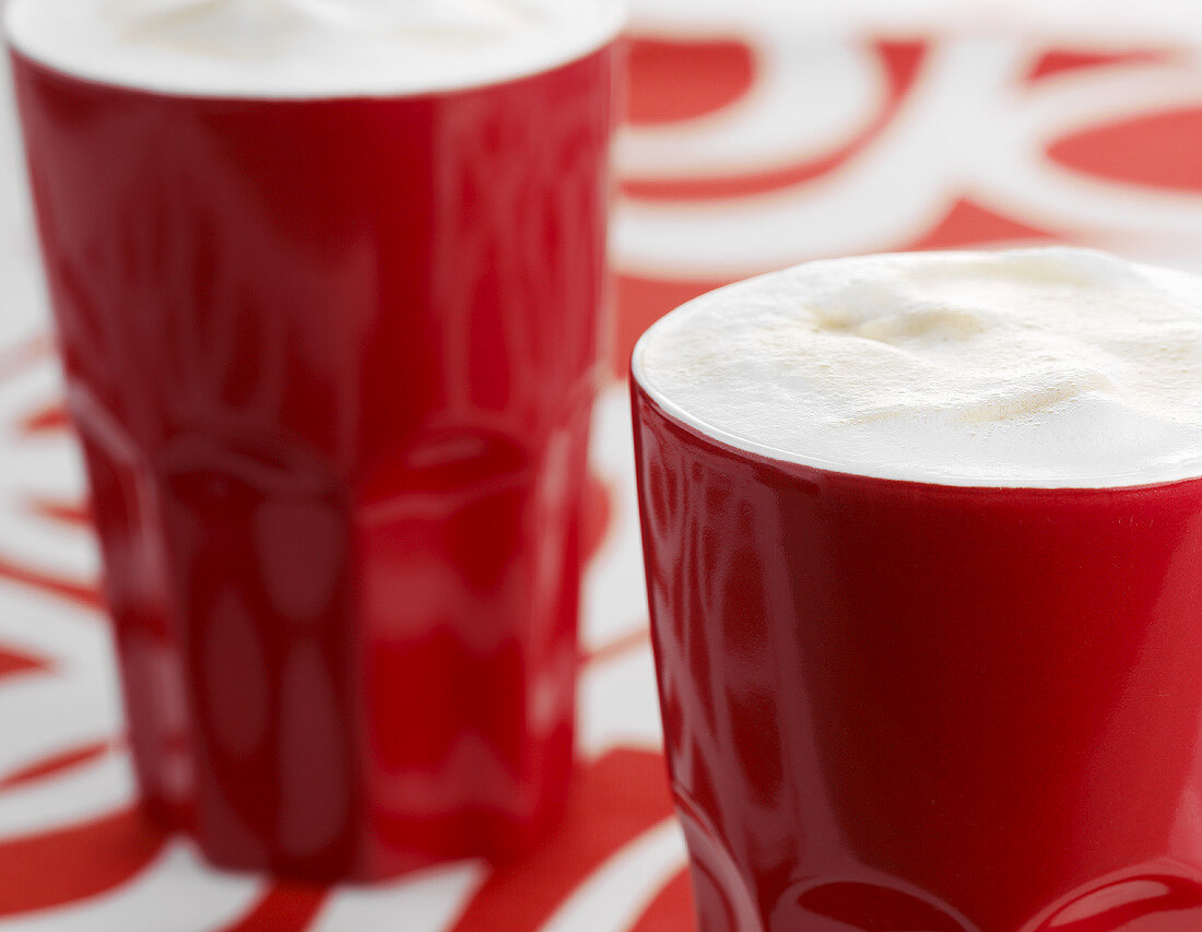 Coffee with milk froth in red beakers