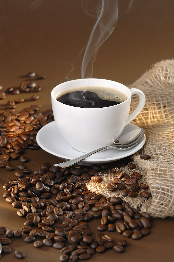 Steaming black coffee and coffee beans