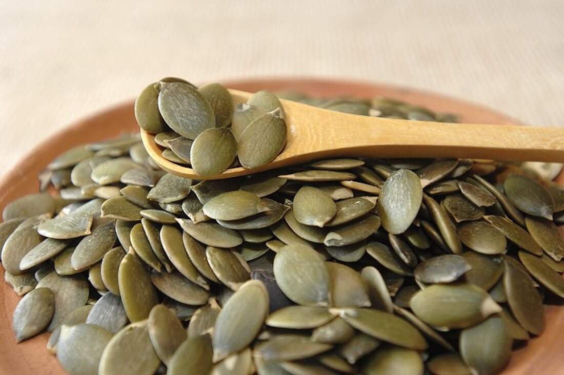 Pumpkin seeds in bowl and on wooden spoon