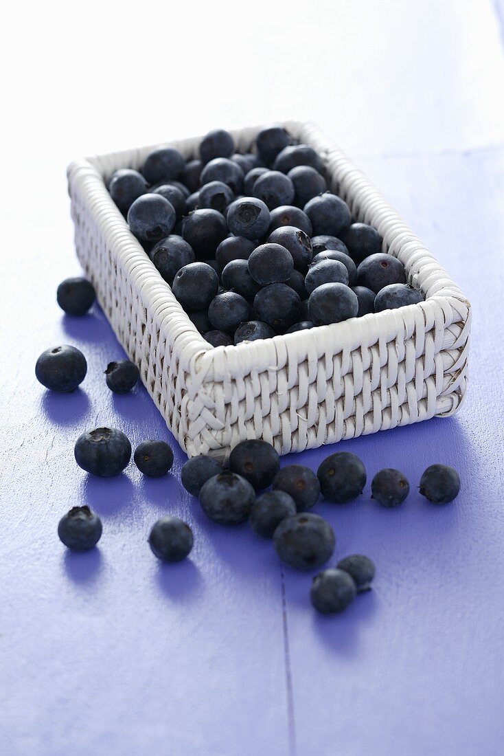 Blueberries in and beside a small basket