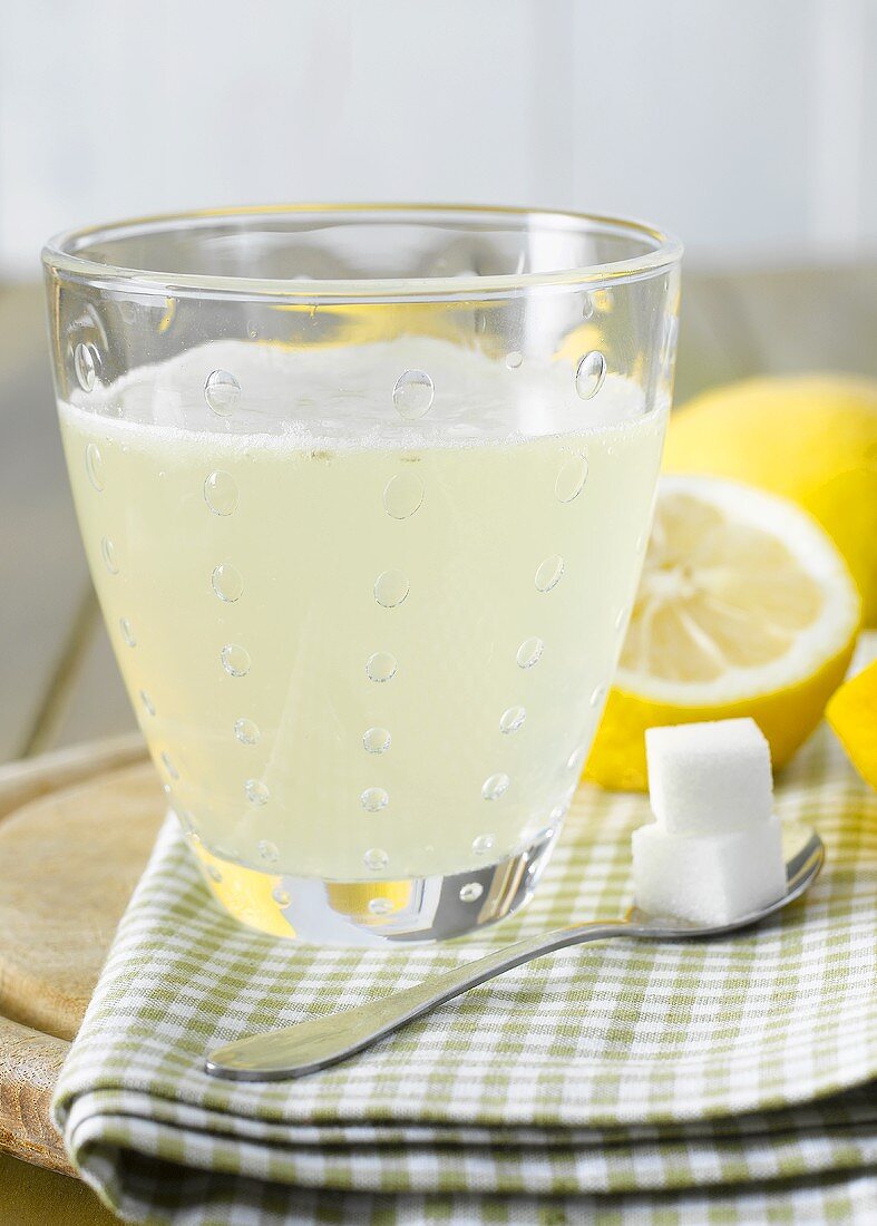Hot lemon with sugar cubes, lemons in background
