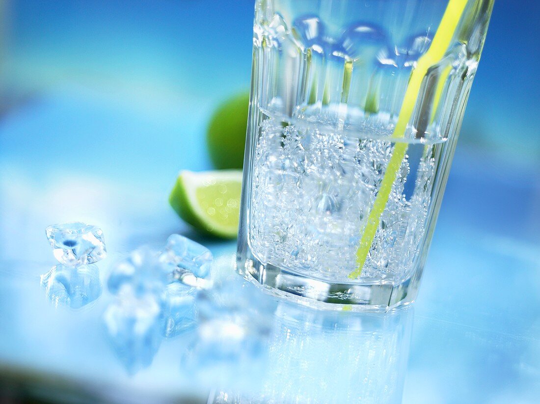 Ein Glas Mineralwasser mit Strohhalm, Crushed Ice und Limette
