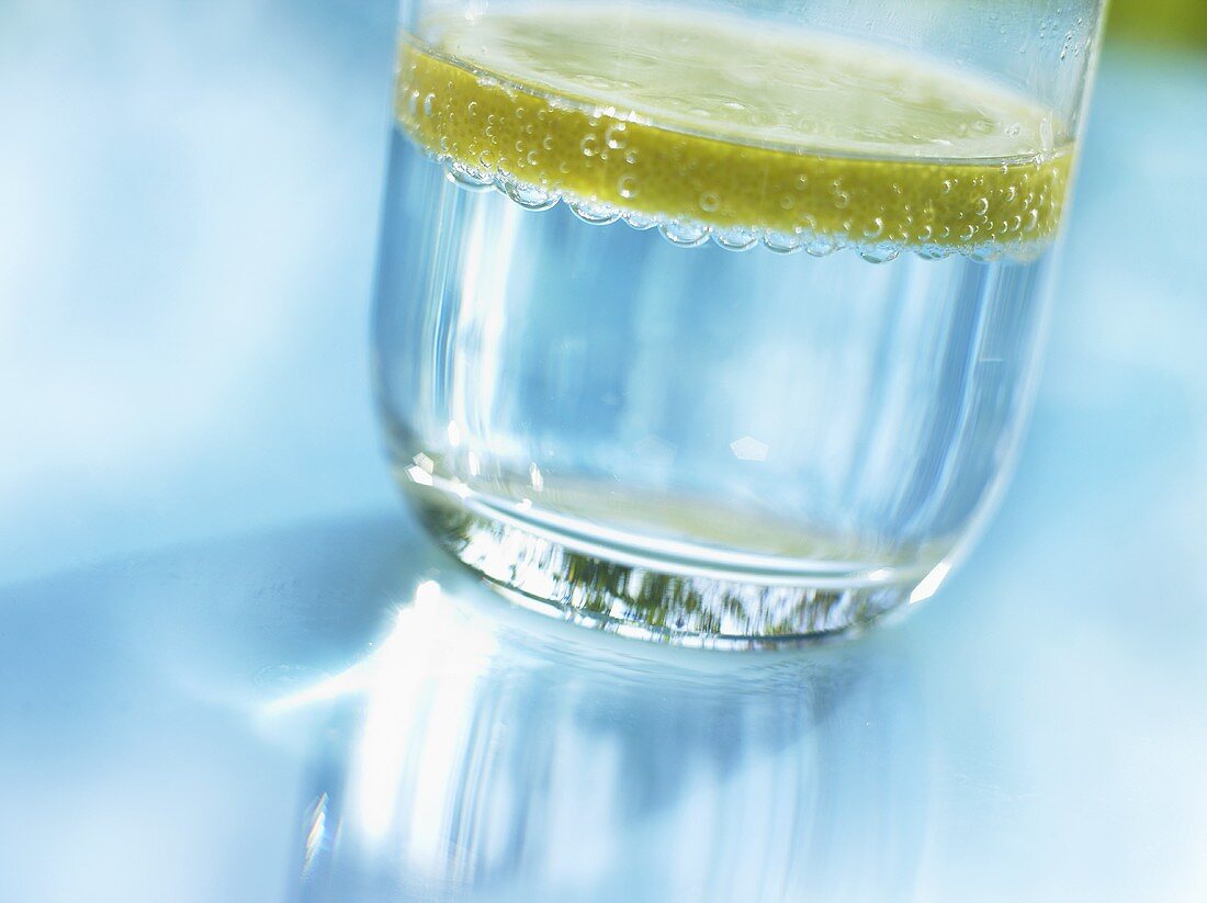 Ein Glas mit Mineralwasser und Zitronenscheibe