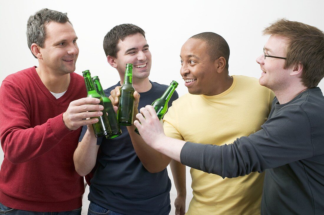 Four men clinking bottles of beer