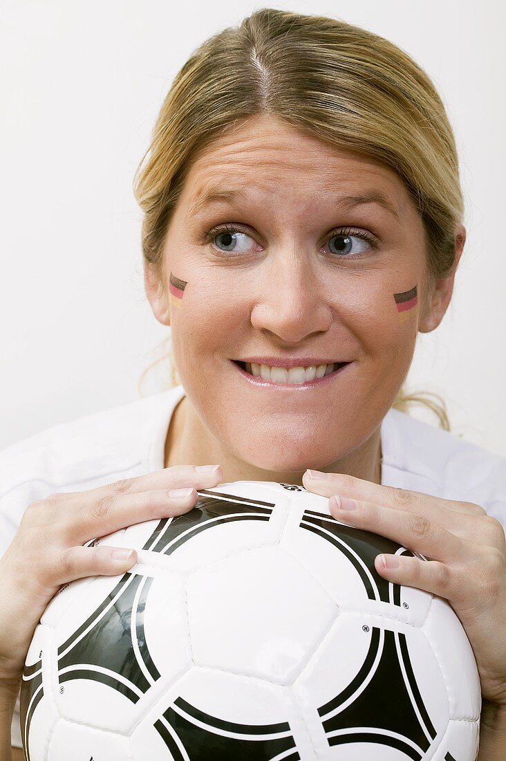 Young woman with German colours on her face holding football