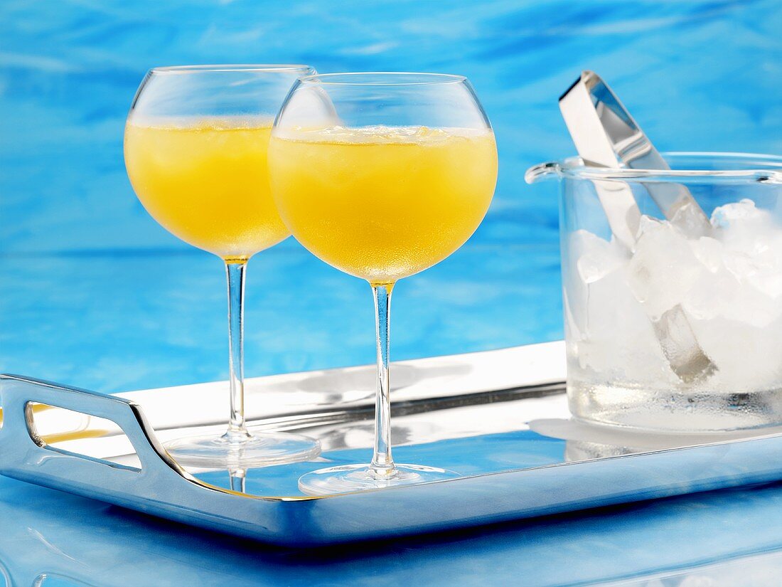 Citrus fruit cocktail and ice cube container on tray