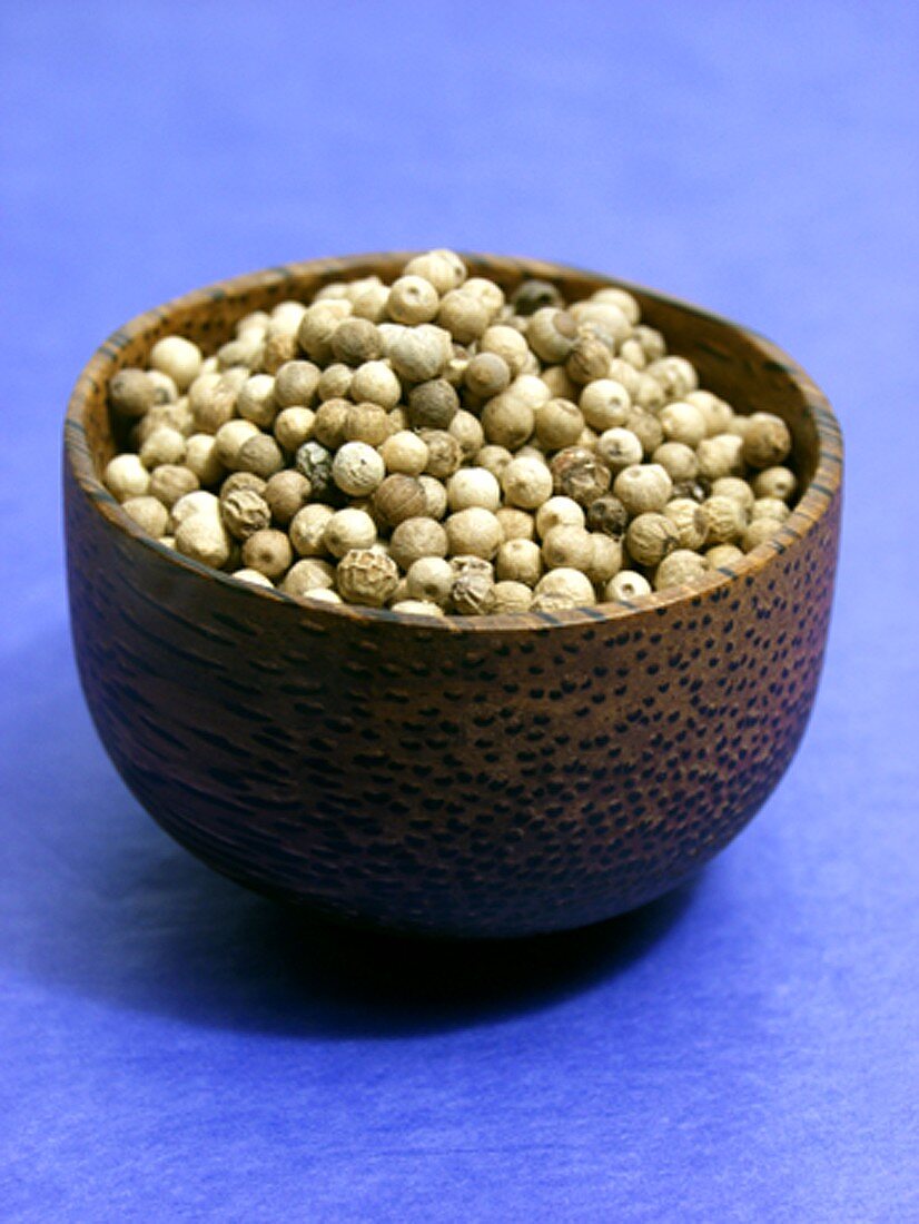 White peppercorns in brown bowl