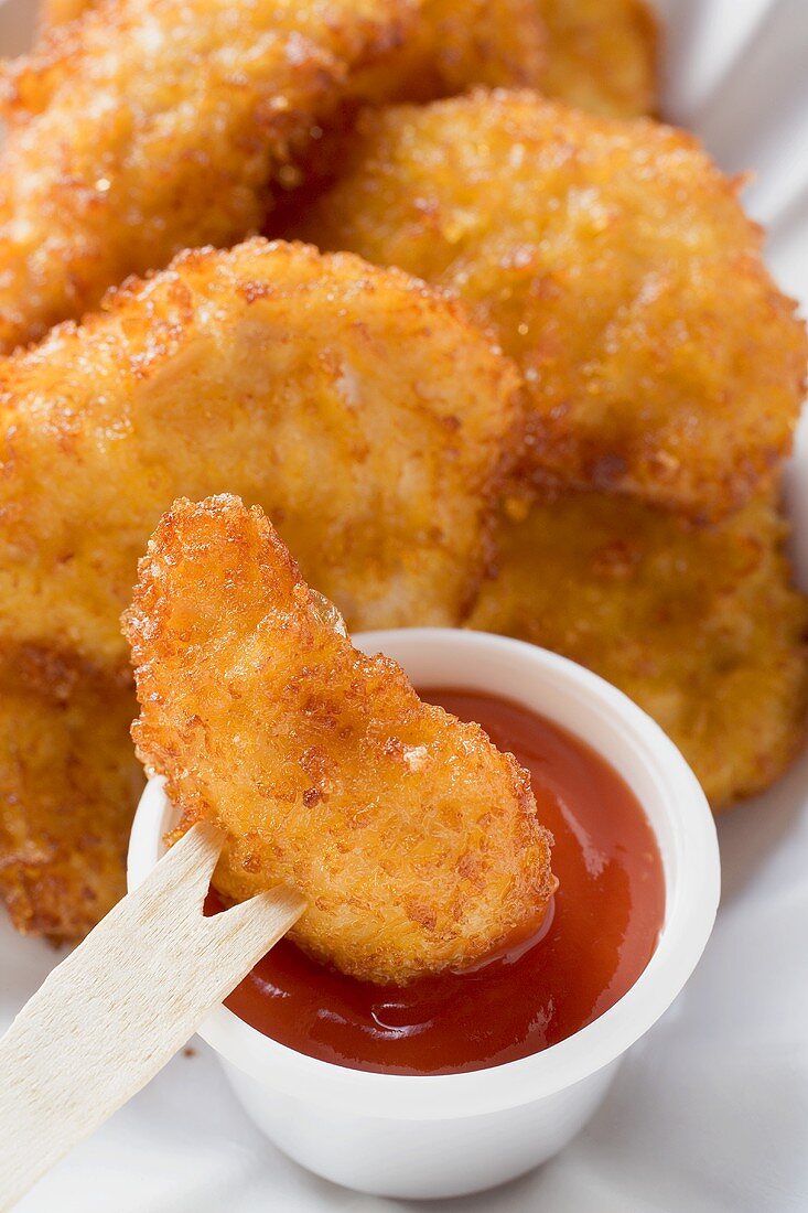 Dipping chicken nugget into ketchup with wooden fork