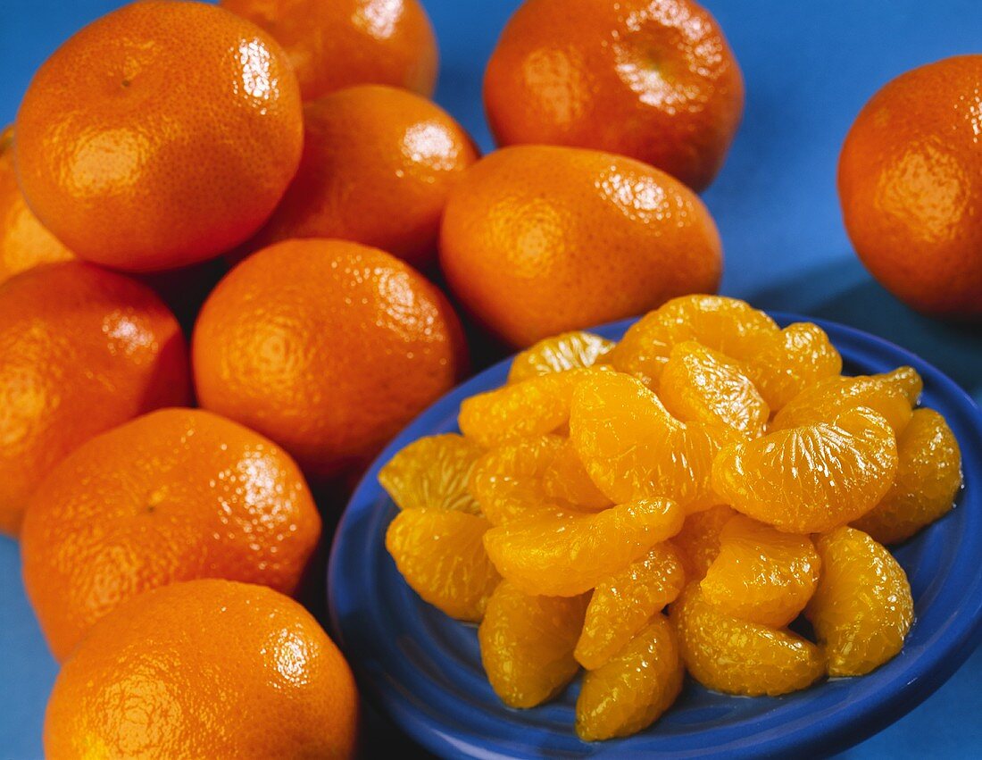 Blue Plate of Orange Segments with Whole Oranges