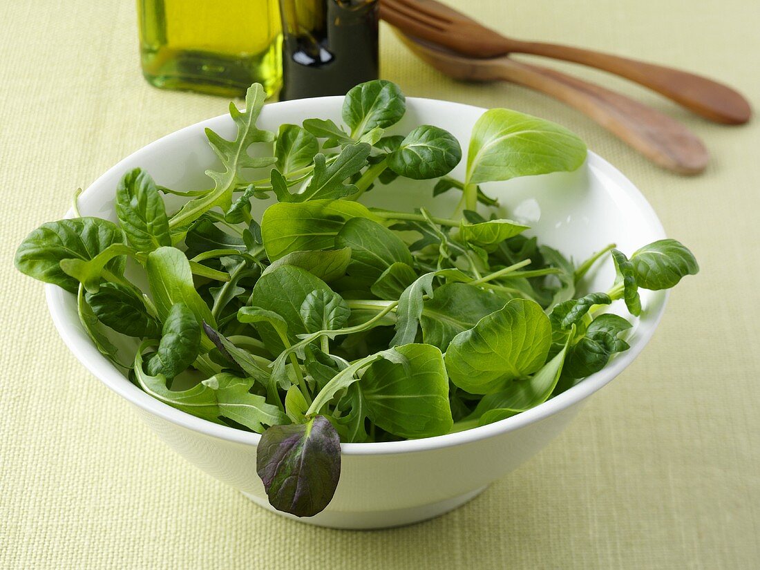 Feldsalat mit Rucola in Schale und Salatbesteck