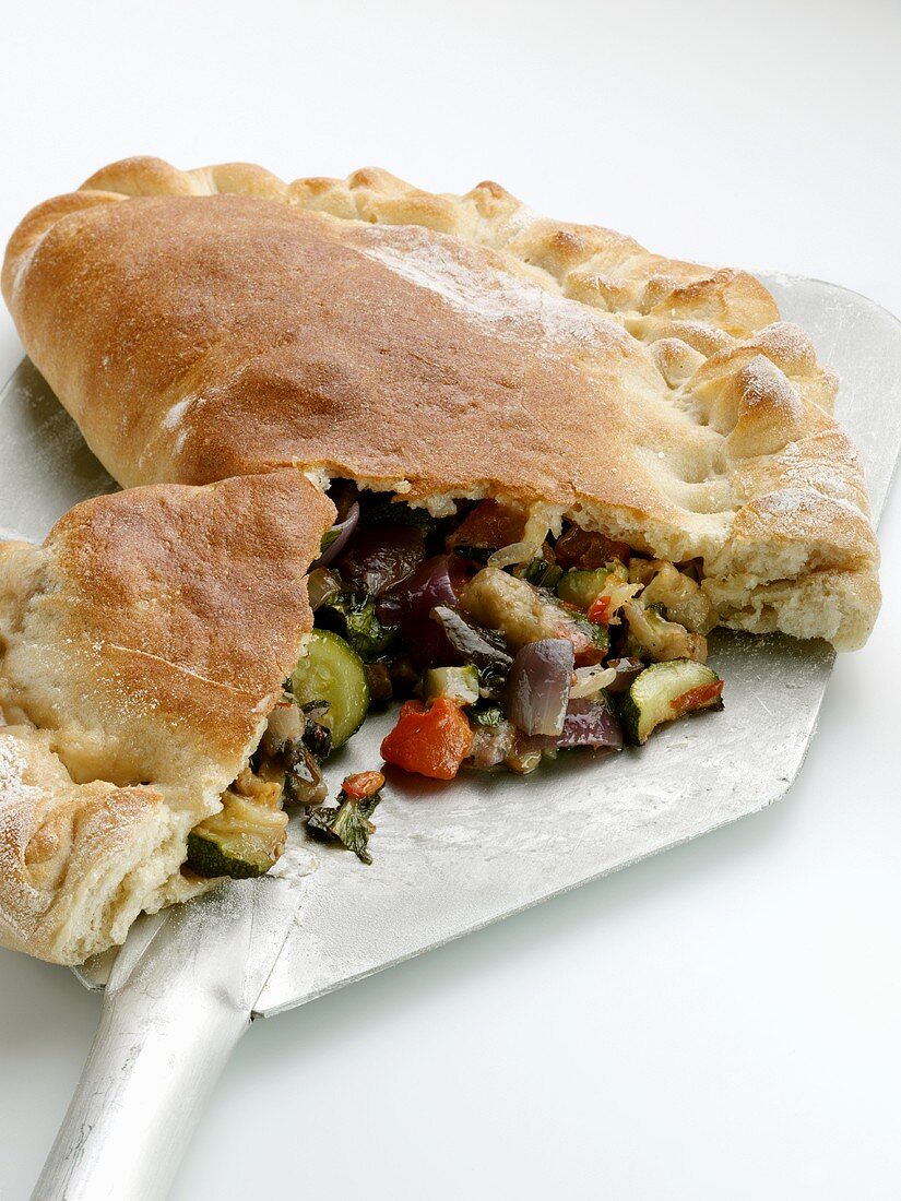 Calzone with vegetable filling on pizza peel