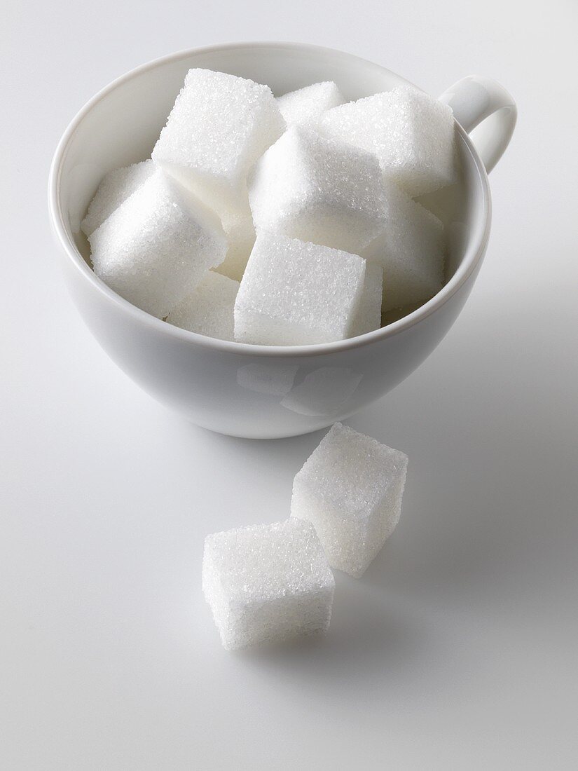 Sugar cubes in and beside white cup