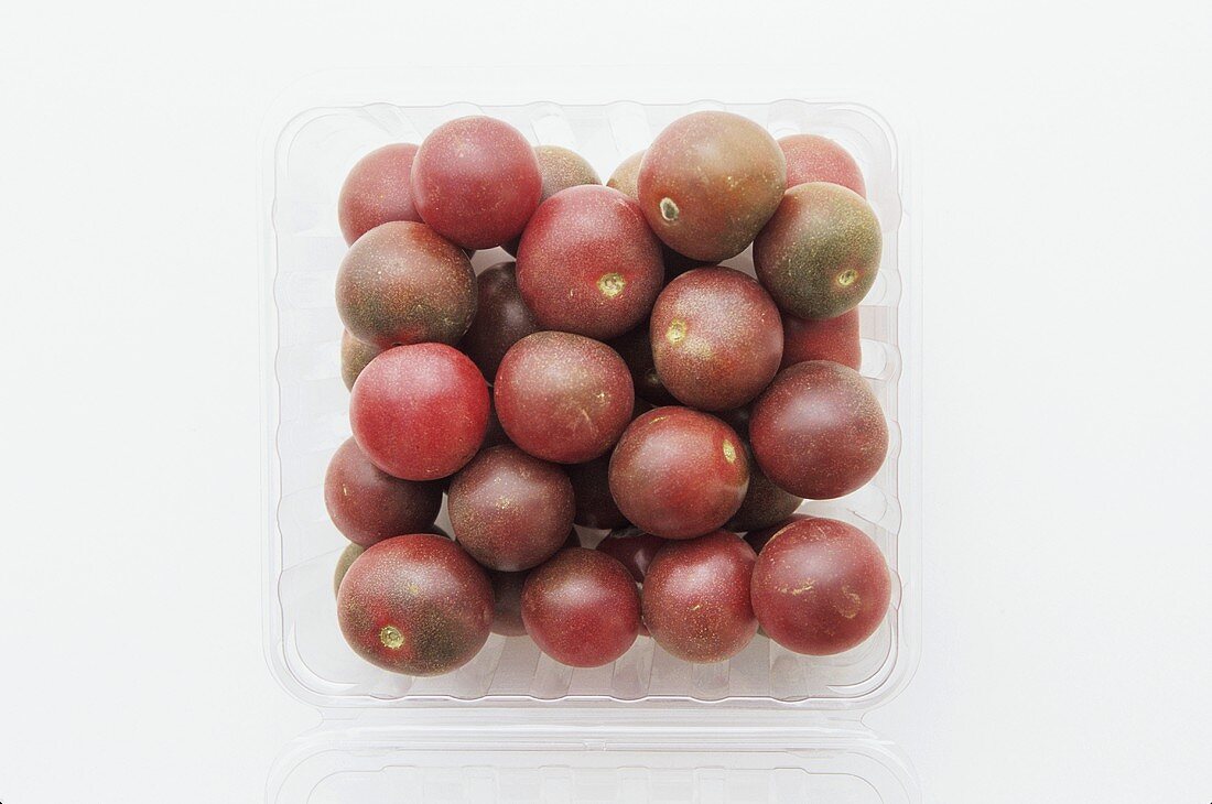 Black cherry tomatoes in a plastic punnet