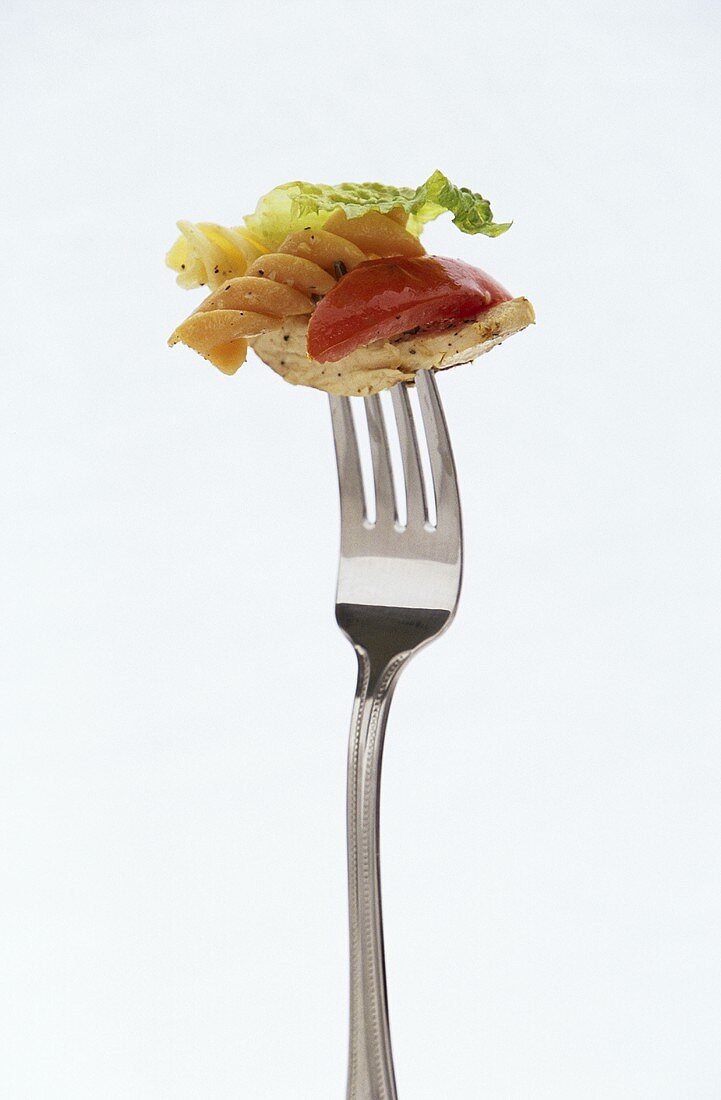 Pasta salad with chicken on fork