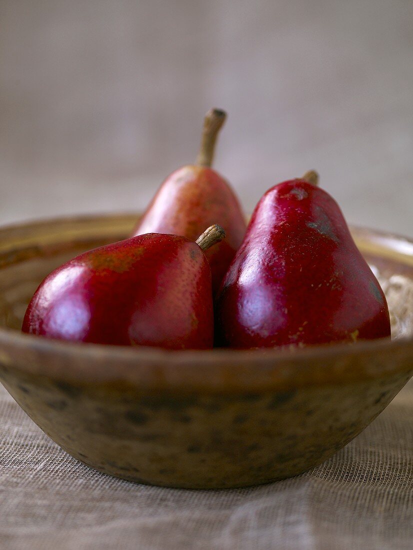 Drei rote Birnen in Holzschale