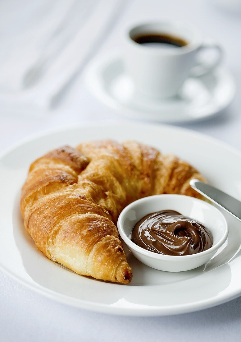 Croissant spread with chocolate and an espresso