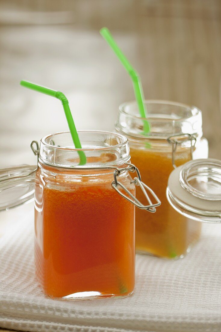 Carrot and orange juice and peach juice in preserving jars with straws