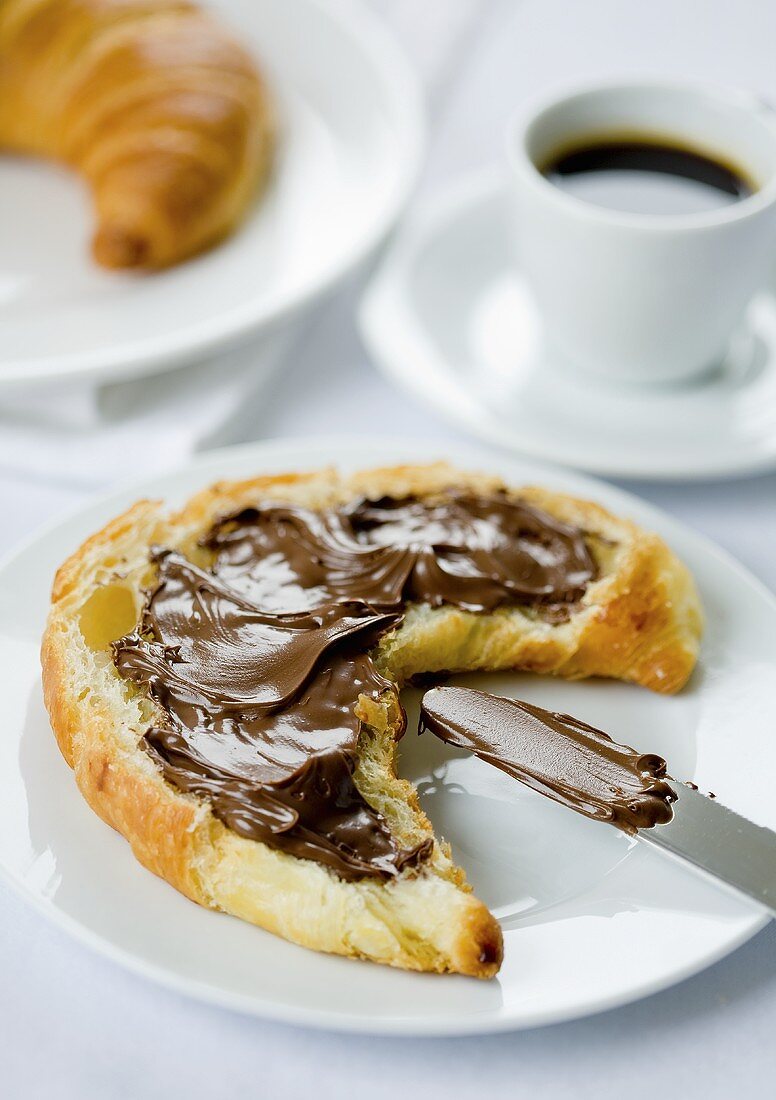 Croissant spread with chocolate and an espresso