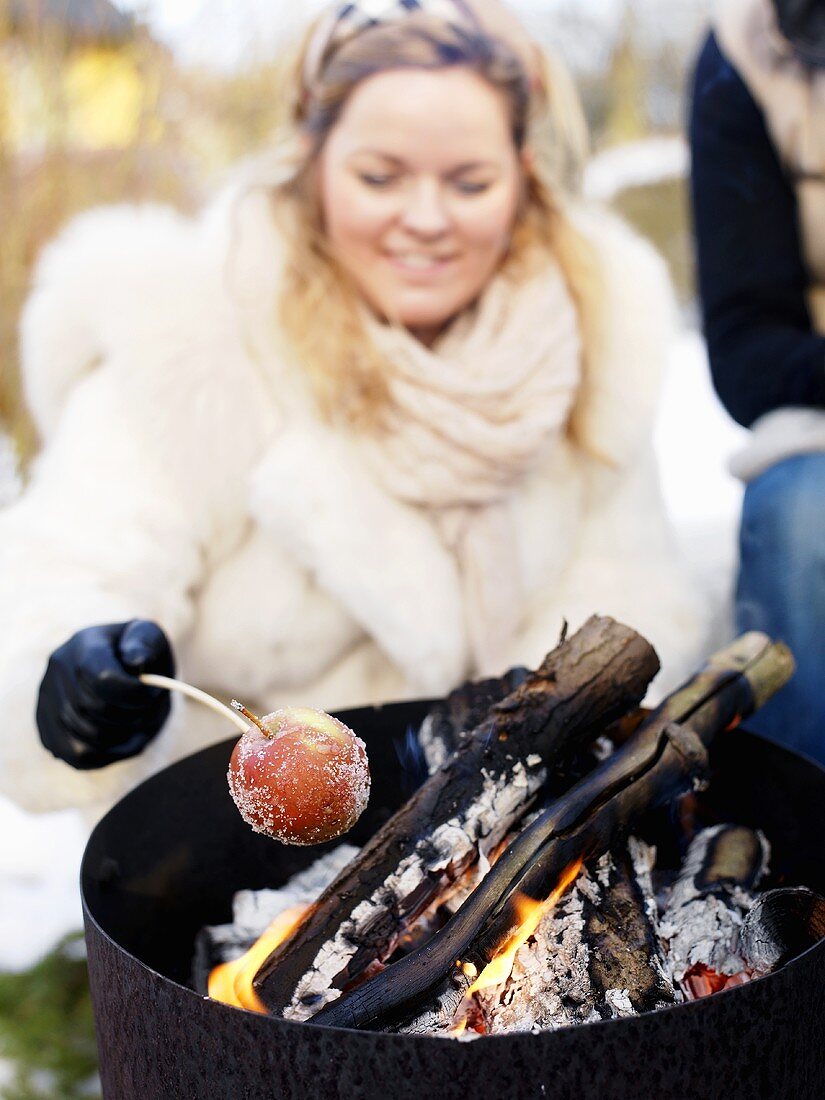 A woman grilling an apple in the winter