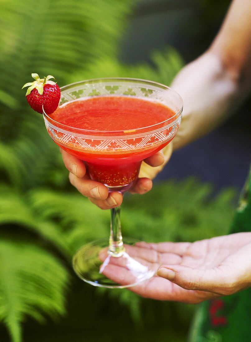 Hands holding a strawberry margarita