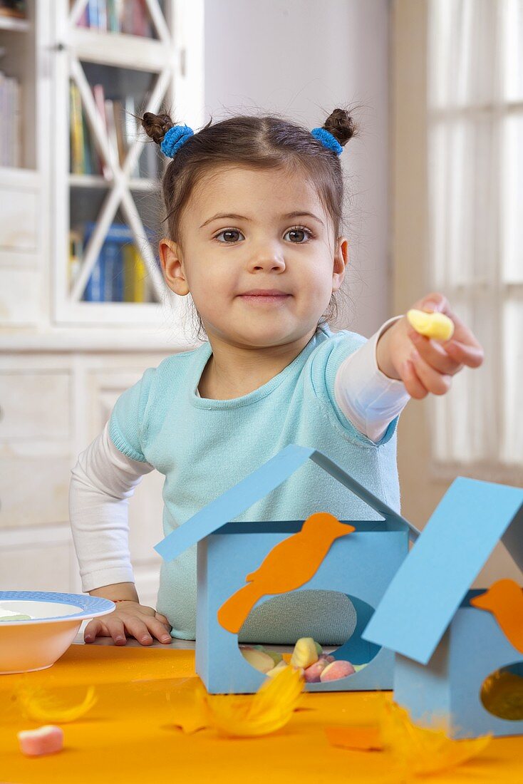 A little girl showing sweets from inside a bird house