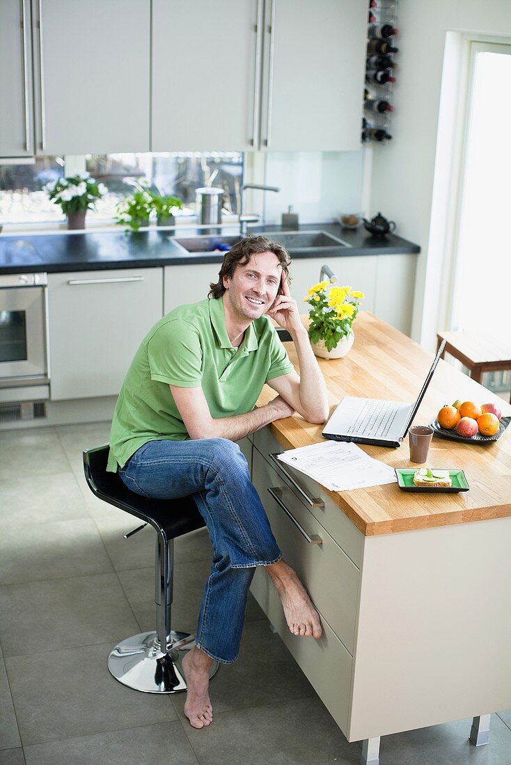 A man with a laptop sitting at a kitchen table