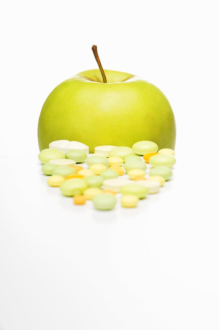 Vitamin tablets and a Golden Delicious apple
