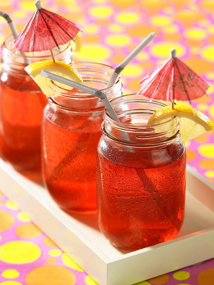 Red berry lemonade in jars with cocktail umbrellas