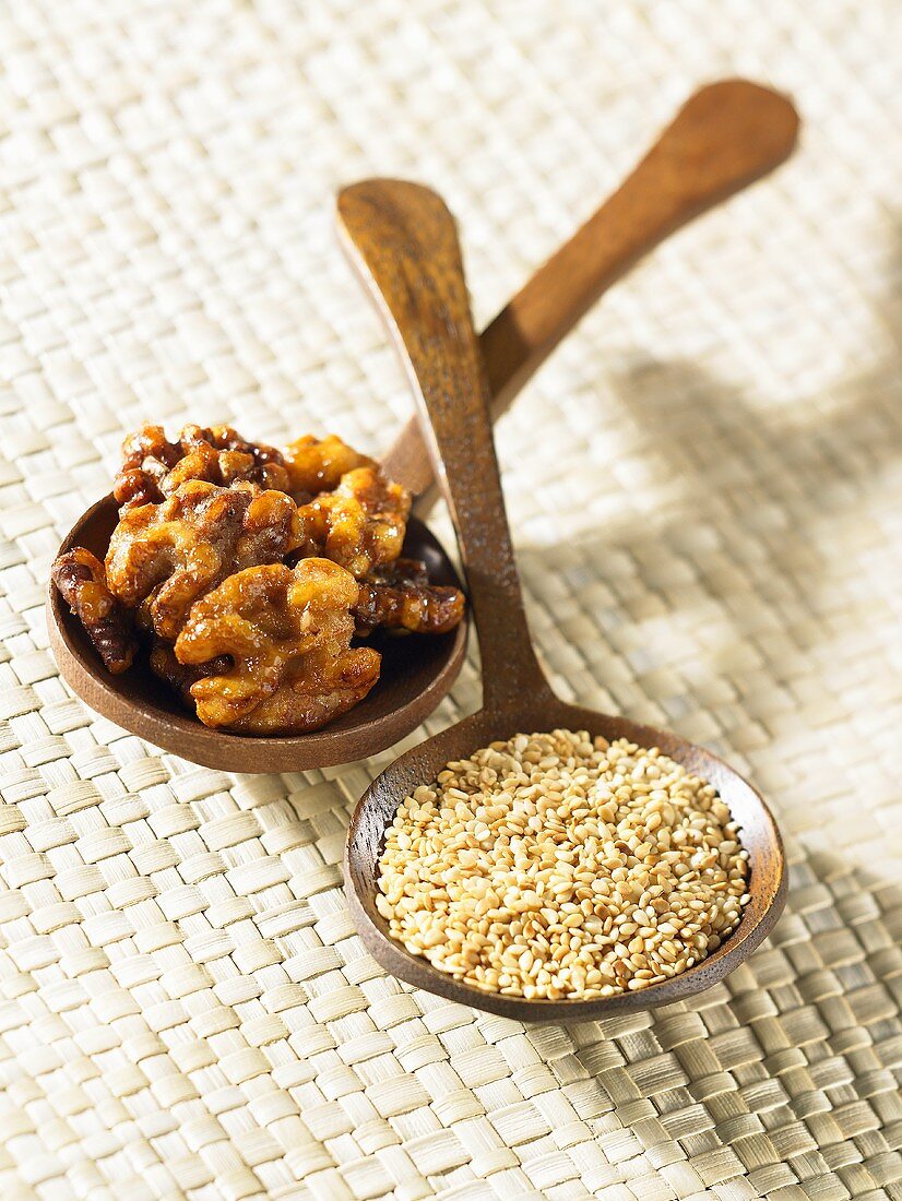 Roasted walnuts and sesame seeds on wooden spoons