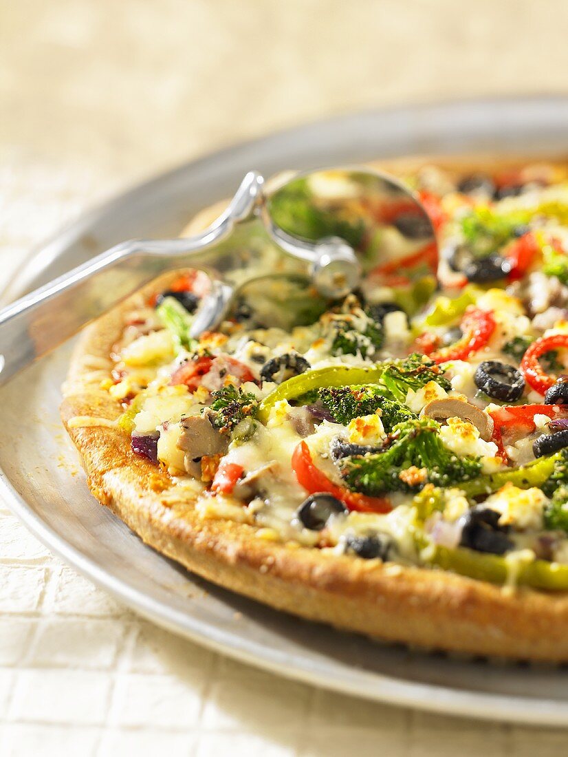 Vegetable pizza with a pizza wheel