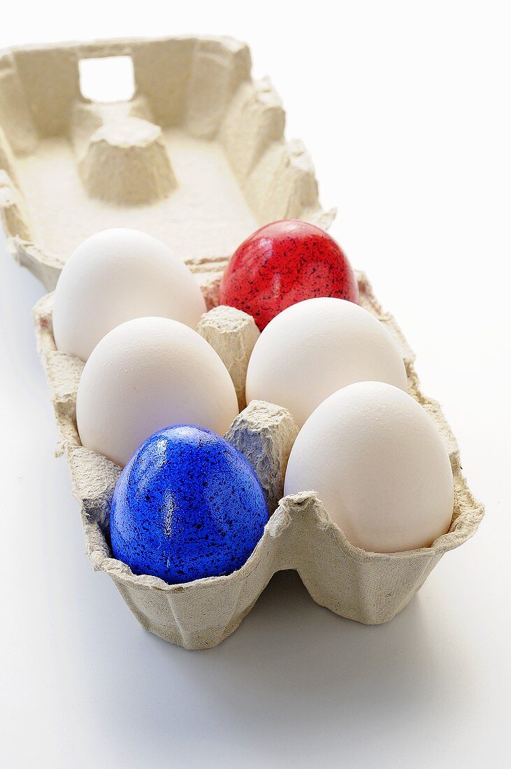 White and coloured eggs in an egg box