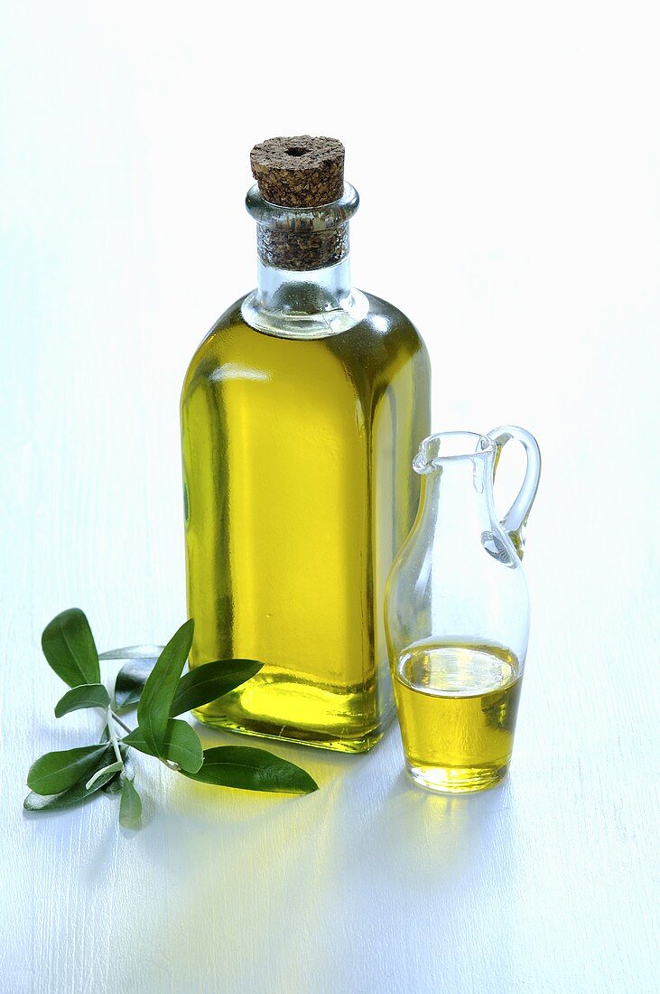 A bottle and a carafe of olive oil with an olive sprig