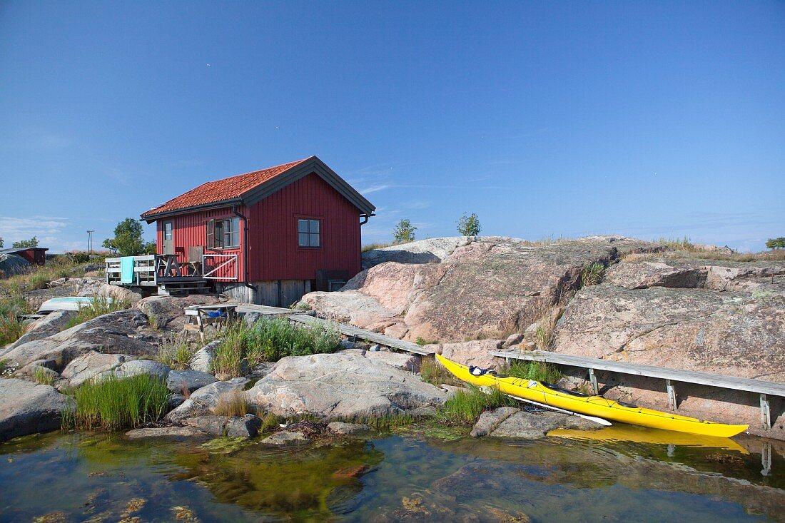 A wooden house and a canoe on a beach (Scandinavia)