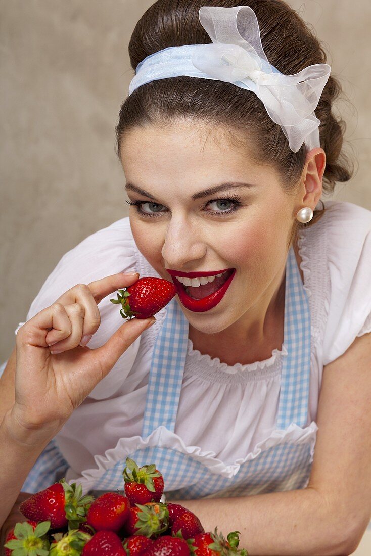Mädchen im Retro-Look isst frische Erdbeeren
