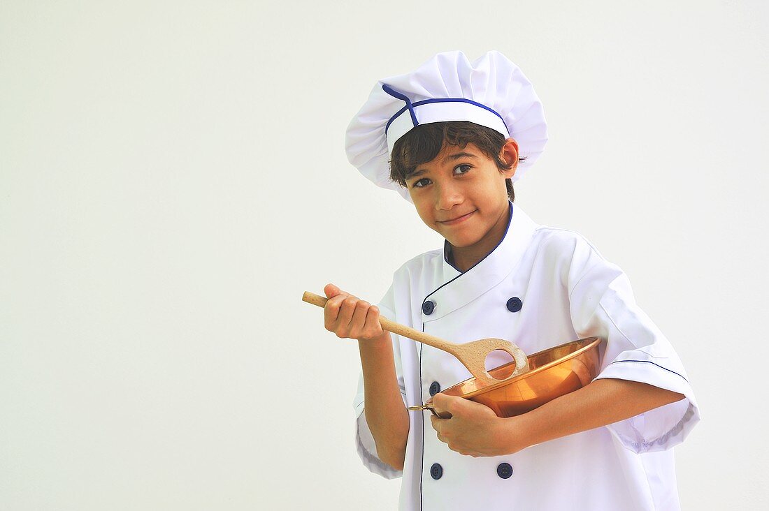 Junge als Koch mit Rührschüssel und Kochlöffel