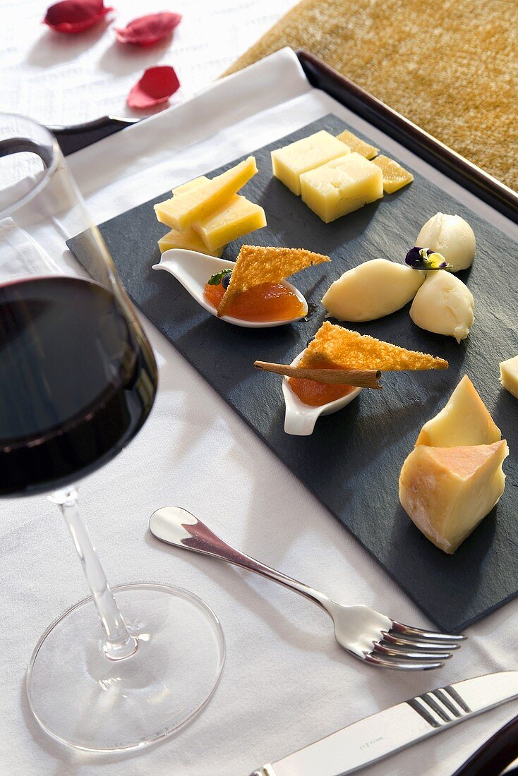 A tray of appitisers (cheese and jam) and a glass of red wine