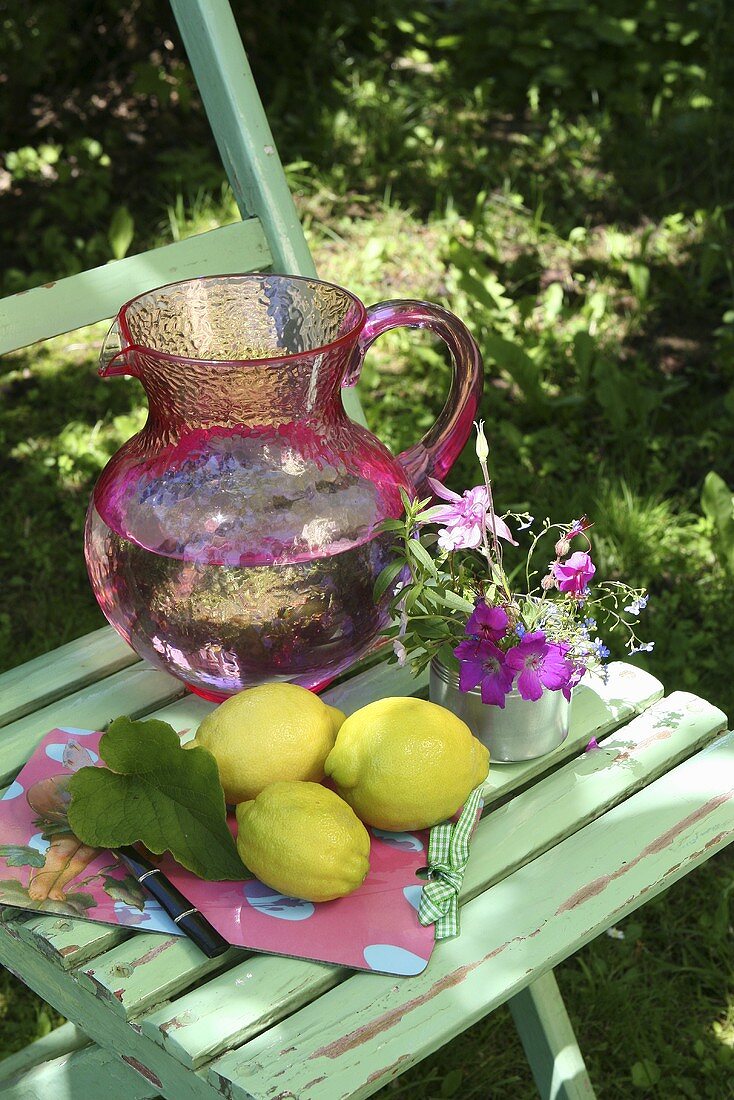 Zitronen und Wasserkrug auf einem Gartenstuhl