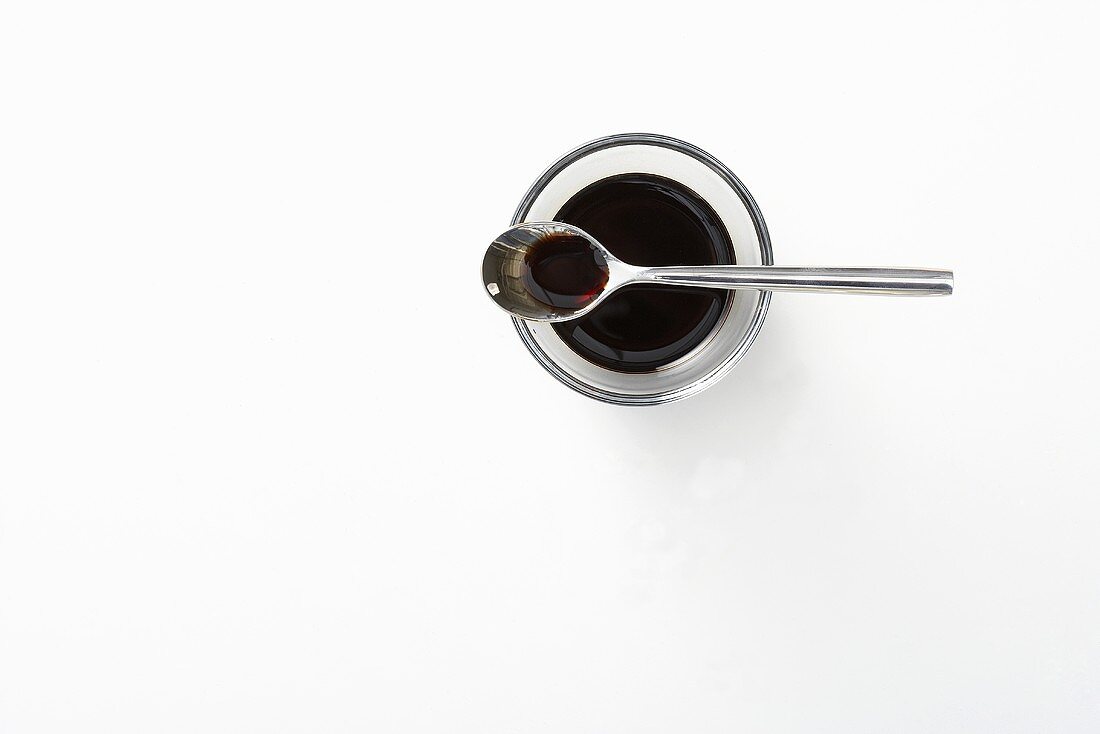 Balsamic vinegar in a glass bowl and a spoon, seen from above