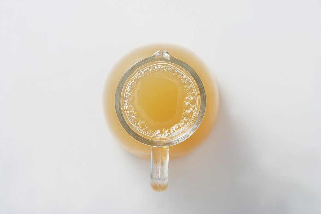 Naturally cloudly apple juice in a glass jug, seen from above