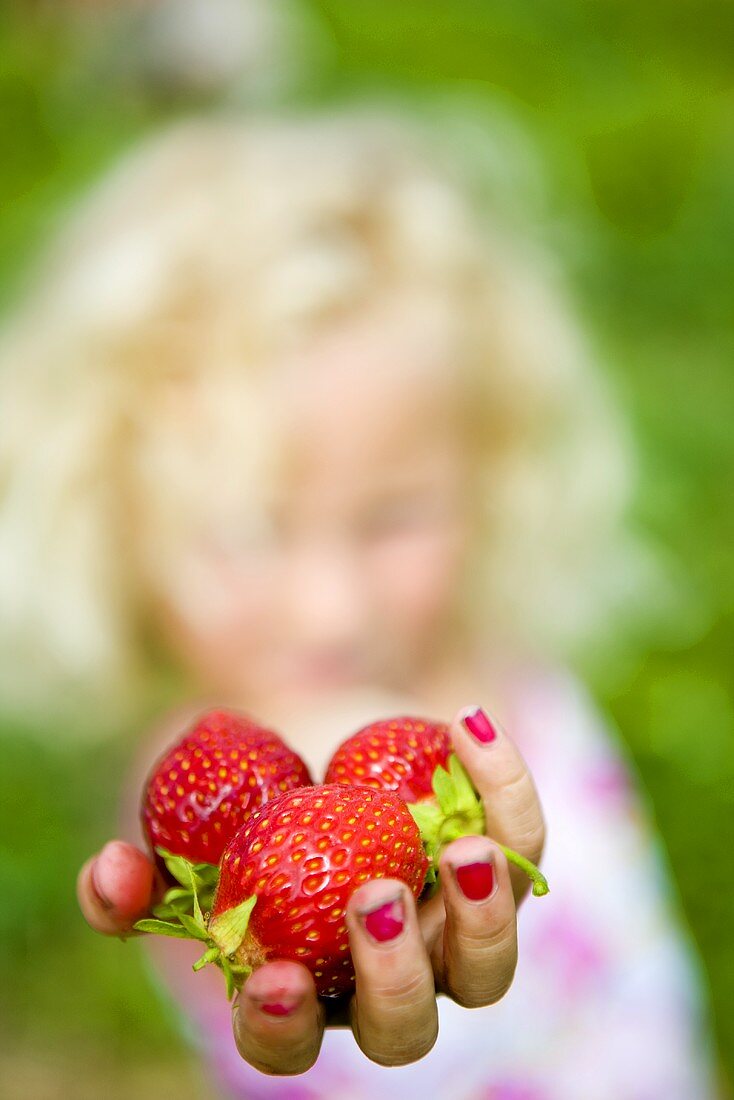 A blonde girl holding strawberries