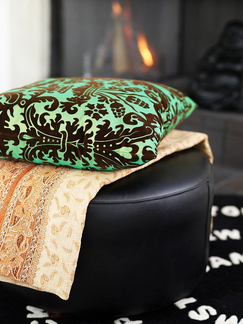 A cushion and a blanket on a leather stool