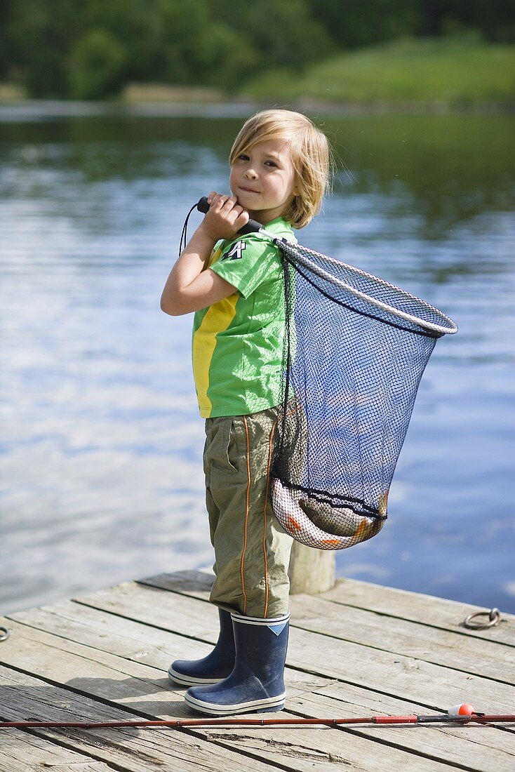 A little boy on a jetty holding a fishing net